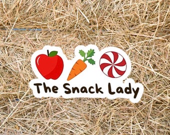 May include: A sticker with the text "The Snack Lady" and illustrations of a red apple, orange carrot, and red and white swirled candy. The sticker is on a background of dry hay.