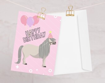 May include: A pink birthday card with a cartoon pony wearing a party hat and balloons. The card says "Happy Birthday" in white text. A white envelope is clipped to the card with a gold binder clip.