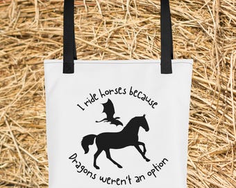 May include: White tote bag with black handles featuring a black silhouette of a horse and a dragon. The text reads "I ride horses because dragons weren't an option."