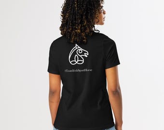 May include: Black t-shirt with a white outline of a horse's head and the text "#TeamIrishSportHorse". The shirt is paired with denim shorts. The image shows the back of a person.