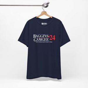 Op de afbeelding: Een marineblauw t-shirt met een witte en rode grafische print die "Baggins Gamgee '24" en "Make Middle-earth Great Again" zegt.