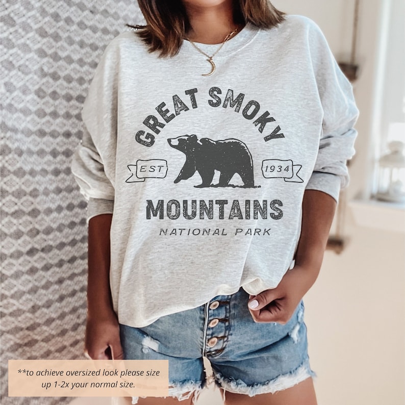 May include: A gray sweatshirt with a black graphic print of a bear and the text "Great Smoky Mountains National Park" with the text "Est 1934".