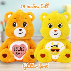 May include: Two plush teddy bears, one orange and one yellow, each 18 inches tall. The orange bear has a heart with "BOUJEE Bear" in glitter font. The yellow bear has a sun design with "MAZLEY" and sunglasses. Both have heart-shaped accents.
