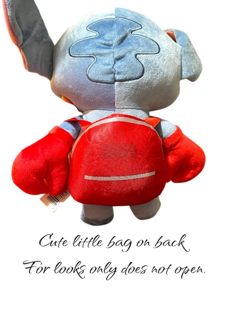 May include: A plush toy of a blue and gray alien character with large red hands and a red backpack. The text on the image says, "Cute little bag on back. For looks only does not open."