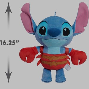 May include: A plush Stitch doll, approximately 16.25 inches tall, in shades of blue, red, and brown. The doll features large ears, a smiling face, and a crab-like outfit. A tag is attached to the doll.