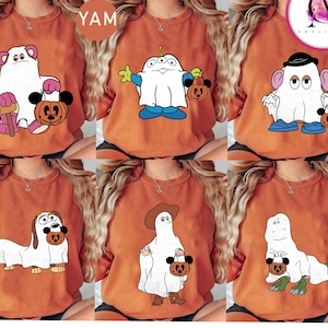 Puede incluir: Seis camisetas naranjas con diseños de personajes de dibujos animados con temática de Halloween. Cada camiseta presenta un personaje diferente, incluyendo un oso, un extraterrestre, el Sr. Potato, un perro, un vaquero y un dinosaurio, todos vestidos de fantasmas y sosteniendo cestas con forma de calabaza.