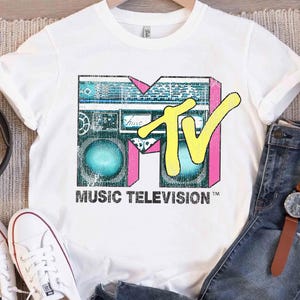 May include: A white ceramic mug with a black handle and the text "But First, Coffee" in a black, bold font. The mug is on a white surface.