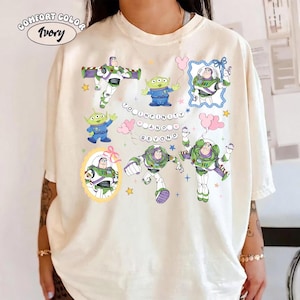 Puede incluir: Camiseta marfil Comfort Color con m&uacute;ltiples im&aacute;genes de Buzz Lightyear y los peque&ntilde;os hombrecillos verdes de Toy Story. La frase "To Infinity and Beyond" tambi&eacute;n est&aacute; presente.