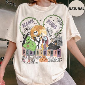 May include: A natural-coloured t-shirt featuring a graphic print of characters from The Nightmare Before Christmas, including Jack Skellington, Sally, and Oogie Boogie. The design includes the text NAME, 2026, OOGIE BOOGIE BASH, and pumpkins.