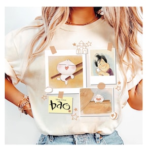 May include: Cream-colored t-shirt featuring a collage of illustrations from the Disney Pixar film "Bao." The design includes images of a dumpling character, a person, and the film's title. The illustrations are arranged with decorative elements.