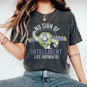 Op de afbeelding: Een donkergrijs T-shirt met een verweerde look met een cartoon afbeelding van Buzz Lightyear uit de Toy Story-filmfranchise. De tekst op het shirt luidt "No sign of intelligent life anywhere".
