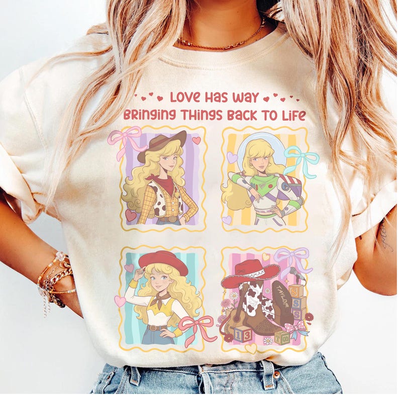 May include: A cream-colored t-shirt featuring a graphic print with four square panels. The text reads, "LOVE HAS WAY BRINGING THINGS BACK TO LIFE." The panels depict a blonde character in various outfits, including a cowgirl and space ranger, plus a cowboy boot.