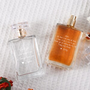 May include: Two clear glass perfume bottles with gold caps. The bottle on the left has the text "Thank you you mean the world Always love you Jessica" etched on it. The bottle on the right has the text "Mom All that I am and all that I hope to be, I owe to you Thank you for being by my side Today and always, Emily" etched on it.