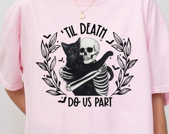 May include: Pink t-shirt with a black and white graphic of a skeleton hugging a black cat. The graphic includes the text "'Til Death Do Us Part".