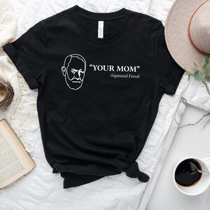 May include: Black t-shirt with a white outline of Sigmund Freud's face and the text "YOUR MOM" -Sigmund Freud.