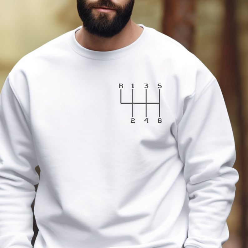 May include: White sweatshirt with a black graphic of a car's gear shift pattern. The pattern includes the letters R, 1, 2, 3, 4, 5, and 6.
