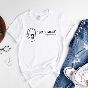 May include: White t-shirt with a black line drawing of Sigmund Freud and the text "YOUR MOM" - Sigmund Freud.