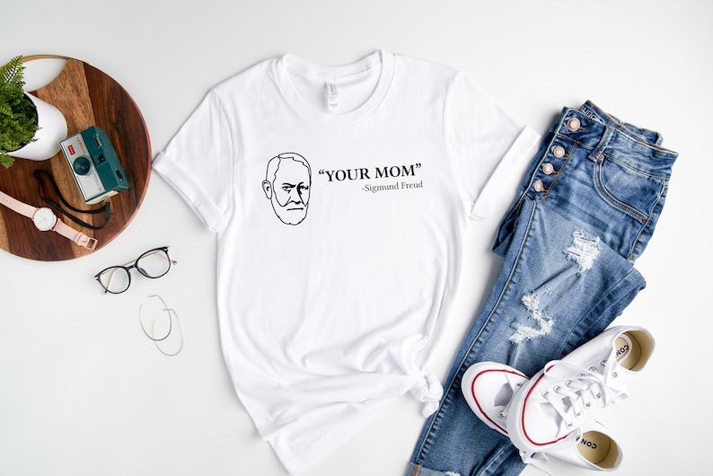 May include: White t-shirt with a black line drawing of Sigmund Freud and the text "YOUR MOM" - Sigmund Freud.
