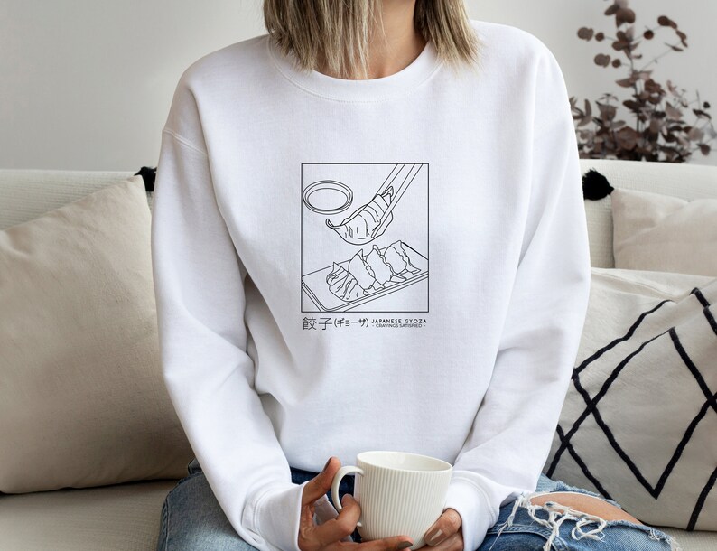 May include: White sweatshirt featuring a black line drawing of a plate of gyoza and chopsticks. The text "餃子 (gyoza) - JAPANESE GYOZA" is printed below the image.
