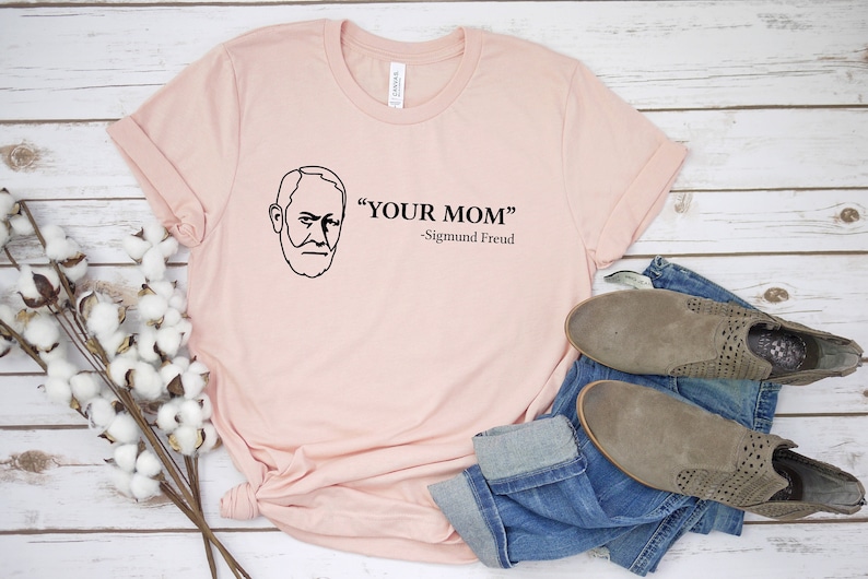 May include: A pink t-shirt featuring a black line drawing of Sigmund Freud and the text "YOUR MOM" -Sigmund Freud.