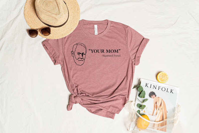 May include: A pink t-shirt with a black line drawing of Sigmund Freud and the text "YOUR MOM" - Sigmund Freud.