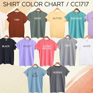 Pu&ograve; includere: Tabella colori di 14 t-shirt con diversi colori e nomi. I colori includono avorio, yam, muschio, burro, spuma di mare, orchidea, nero, viola, anguria, grigio, bianco, blu ghiaccio e pepe.