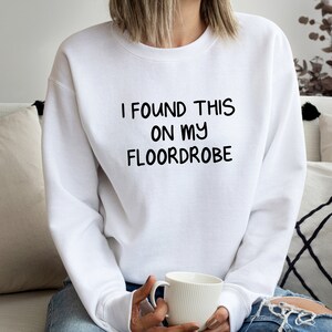 May include: White sweatshirt with the text "I found this on my floordrobe" printed in black.