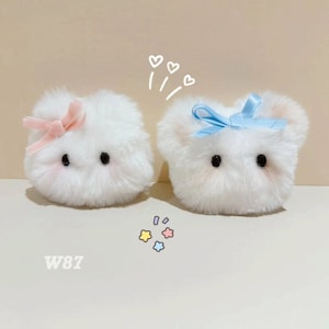May include: Two white plush toys with embroidered faces and bows. The toy on the left has a pink bow and the toy on the right has a blue bow. The toys are facing each other and there are hearts drawn above them. The text "W87" is written below the toys.