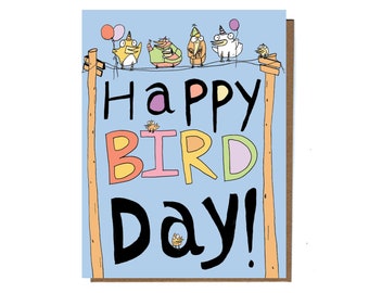 May include: A greeting card with a light blue background and the words "Happy Bird Day!" in colorful letters. The card features cartoon birds perched on a wire, some holding balloons. The card has a brown border.