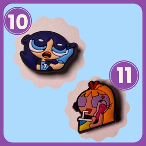 May include: Two cartoon character charms, one with blue hair and a blue shirt, the other with yellow hair and a pink shirt. The charms are numbered 10 and 11.