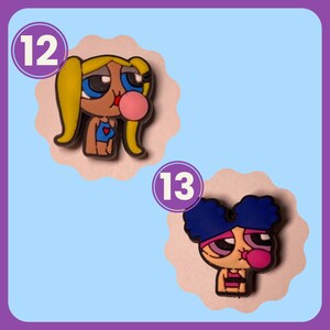 May include: Two cartoon character charms with numbers 12 and 13. The charms are pink, blue, yellow, and white. The characters are blowing bubble gum.