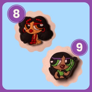 May include: Two cartoon character charms, one with black hair and red clothing, the other with black hair and green clothing. The charms are numbered 8 and 9.