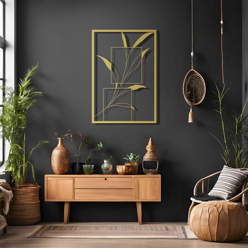 May include: A gold metal wall art piece featuring a stylised plant design with geometric shapes. The art is hanging on a dark grey wall above a wooden console table with decorative items.