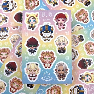 May include: A sheet of colorful stickers featuring various characters from the video game Fire Emblem: Three Houses. The stickers are on a rainbow background with stars and the text "LALIH0!" and "BurnDraws".