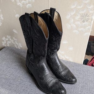 May include: A pair of black leather cowboy boots with intricate stitching and a pointed toe.