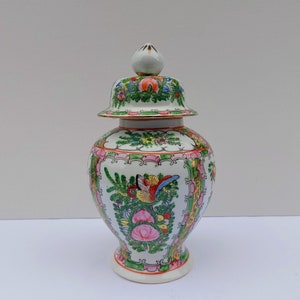 May include: A white porcelain jar with a lid, decorated with a floral pattern in shades of pink, green, and yellow. The jar has a traditional Chinese design.