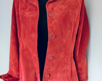 May include: A red suede jacket with a classic collar and button closure. The jacket has long sleeves and a tailored fit. The color is a vibrant, warm red, and the suede texture is visible. This outerwear piece is suitable for various occasions.