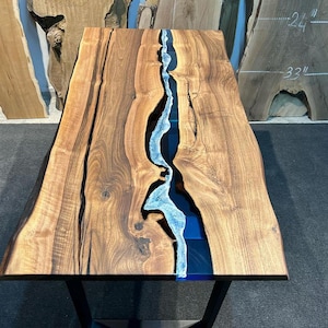 Könnte beinhalten: Eine Tischplatte aus Holz mit einem blauen und weißen Harzfluss, der in der Mitte verläuft. Die Tischplatte ist etwa 84 cm breit und 61 cm tief.