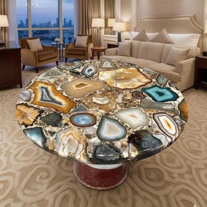 Könnte beinhalten: Ein runder Couchtisch mit einer Mosaikplatte aus polierten Achatscheiben in Braun-, Beige-, Blau- und Weißtönen. Der Tisch hat einen roten Sockel und steht in einem luxuriösen Hotelzimmer.