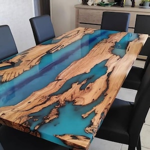 May include: A large wooden dining table with a blue and green epoxy resin inlay. The table is surrounded by black chairs.