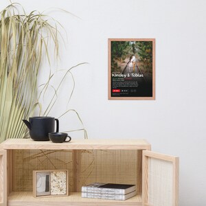 May include: A framed photograph of a couple embracing on a railway track. The photo is in a light wood frame and has a white background. The text "Kinsley & Tobias" is printed in red at the bottom of the photo.