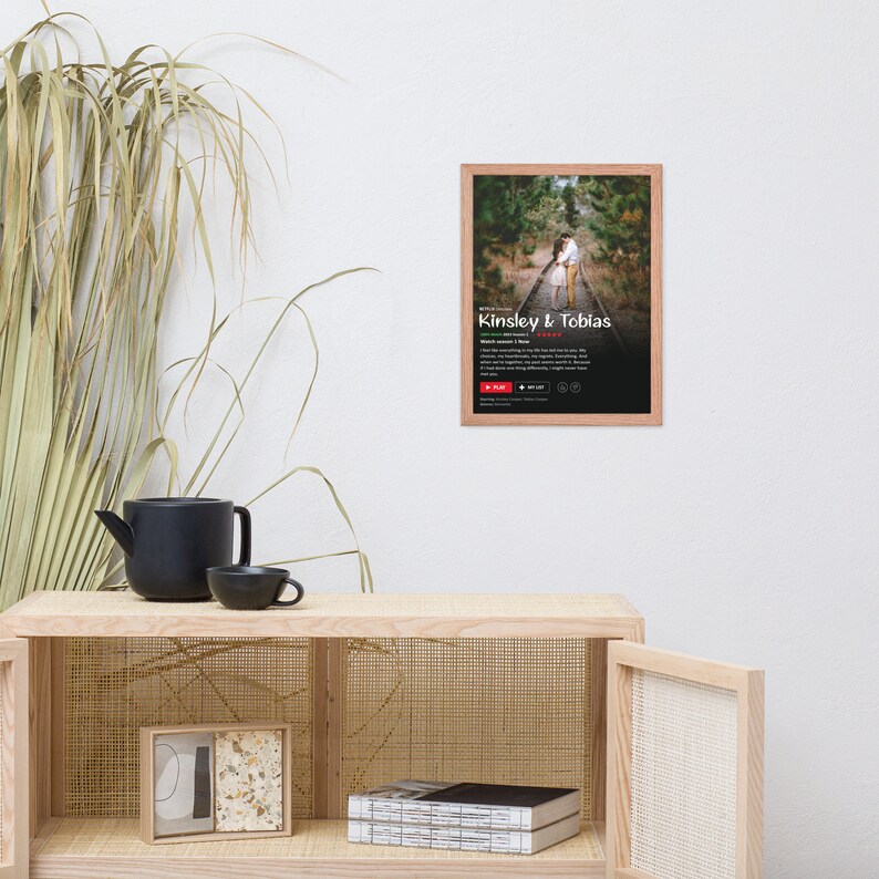 May include: A framed photograph of a couple embracing on a railway track. The photo is in a light wood frame and has a white background. The text "Kinsley & Tobias" is printed in red at the bottom of the photo.