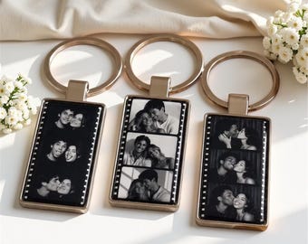 May include: Three rectangular metal keychains with gold-toned frames and split rings. Each keychain features a vertical film strip design containing three black and white photographs of couples in various poses, including smiling and kissing.