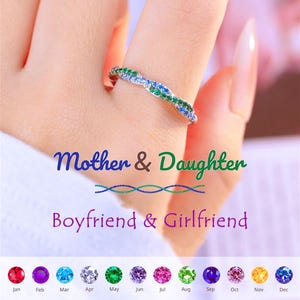May include: A silver ring with a woven design, adorned with green, blue, and clear gemstones. The ring is on a finger. The image includes the text "Mother & Daughter" and "Boyfriend & Girlfriend" with a selection of colorful gemstones.