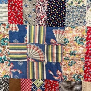 Puede incluir: Un edredón de retazos con una variedad de patrones y colores de tela. El edredón presenta cuadrados de estampados rojos, azules, blancos y florales. Algunos cuadrados tienen rayas, lunares y diseños de abanicos. El edredón es una mezcla de telas vintage y modernas.