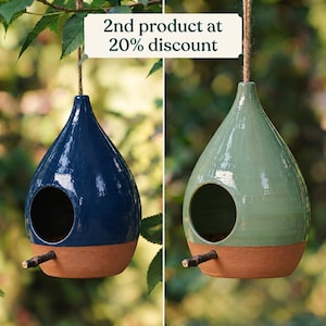 Può includere: Due casette per uccelli in ceramica a forma di goccia appese a uno spago. Una è blu scuro, l'altra verde salvia. Entrambe presentano un foro d'ingresso circolare, un piccolo posatoio in legno e una base in terracotta. Testo: 2nd product at 20% discount.