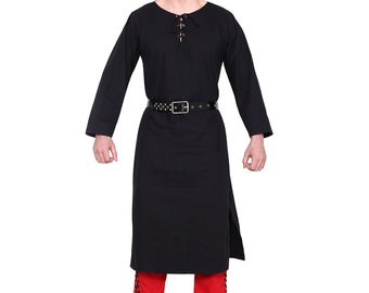 May include: A black tunic with long sleeves and a laced neckline, worn with a black belt and red trousers. The outfit includes brown boots. The tunic has a side slit.