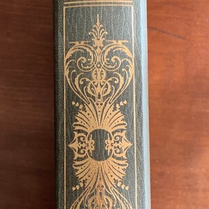 Peut inclure: Un livre relié vert avec des lettres dorées et des accents décoratifs. Le titre est "Across the Wide Missouri" de Bernard DeVoto.
