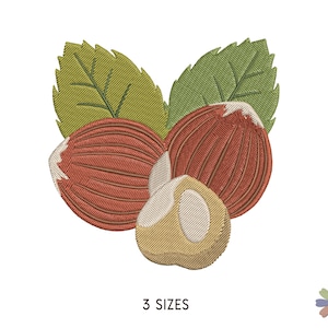 Puede incluir: Tres avellanas bordadas con hojas verdes. Las avellanas son marrones y beige con un aspecto texturizado.