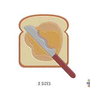 Puede incluir: Diseño bordado de una rebanada de pan con mantequilla de cacahuete y un cuchillo para untarla. El pan es beige, la mantequilla de cacahuete es marrón y amarilla, y el cuchillo es gris con un mango rojo.